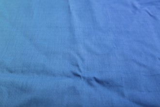 Fragment of smooth cotton blue tissue. Side view, natural textile background and texture