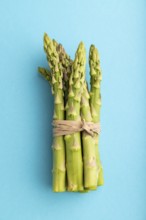 Bunch of fresh green asparagus on blue pastel background. Top view, flat lay, close up. harvest,