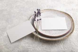 White paper invitation card, mockup with lavender on ceramic plate and gray concrete background.