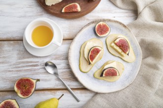 Summer appetizer with pear, cottage cheese, figs and honey on a white wooden background and linen