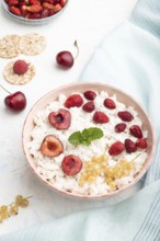 Rice flakes porridge with milk and strawberry in ceramic bowl on white concrete background and blue