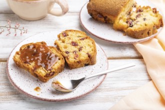 Homemade cake with raisins, almonds, soft caramel and a cup of coffee on a white wooden background