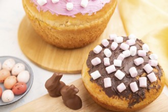 Homemade glazed and decorated easter pies with chocolate eggs and rabbits on a white concrete