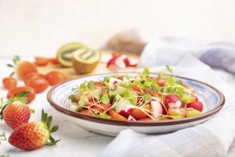 Vegetarian fruits and vegetables salad of strawberry, kiwi, tomatoes, microgreen sprouts on white