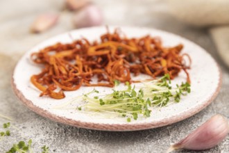 Fried Cordyceps militaris mushrooms on brown concrete background with microgreen, herbs and spices.