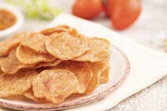 Slices of dehydrated salted meat chips with herbs and spices on gray concrete background and white