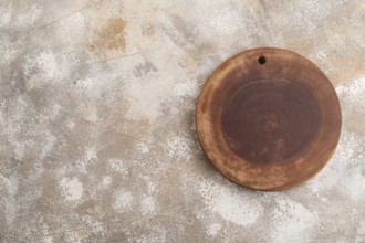 Empty round wooden cutting board on brown concrete background. Top view, copy space, flat lay