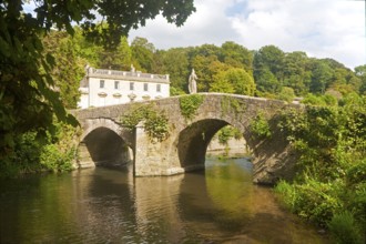 Bridge crossing the River Frome and the classical Georgian facade of Iford Manor, near Freshford,