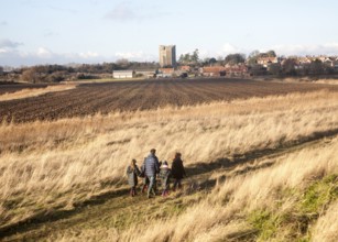 Family walking by the village and castle looking across fields, Orford, Suffolk, England, United