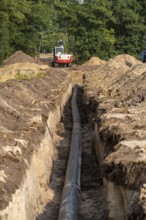 Laying of district heating pipes, next to a field, with maize, the district heating comes from a