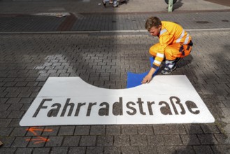 Application of road markings for a cycle lane, Rüttenscheider Straße in Essen, in the shopping and