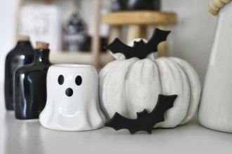 Black and white Halloween decoration with ghost shaped candle, pumpkin, wooden bats and potion