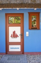 Colourful front door in brown, white and blue with a sailing ship as a motif and matching window