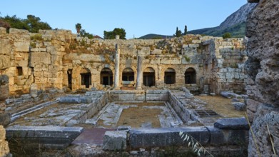 Courtyard of ancient ruins with columns and a clear sky in the background, Peirene Fountain,