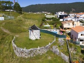 Windmill on a hill with surrounding houses and fences in a small village, aerial view, mill,