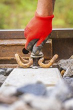 Close-up of a red-gloved hand working on a tool on rails, track construction, Hermann Hessebahn,