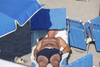 Man on a sun lounger, sunbathing on the beach of Diano Marina, Italy, 14/08/2024, Diano Marina,