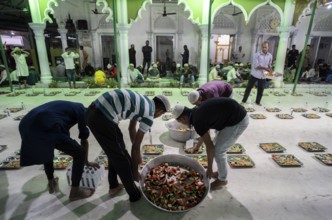 Volunteers distribute and arrange rows of 'iftar' meal for devotees to break their fast, during the