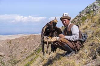 Traditional Kyrgyz eagle hunter with eagle in the mountains, near Kysyl-Suu, Kyrgyzstan, Asia