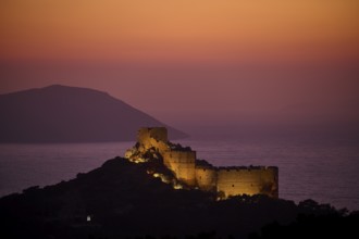 Illuminated castle ruins at dusk with a view of the sea and the surrounding mountains, Kritinia