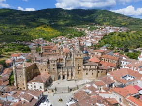 Aerial view of an old monastery with red roofs, surrounding mountains and green hills, depicted in