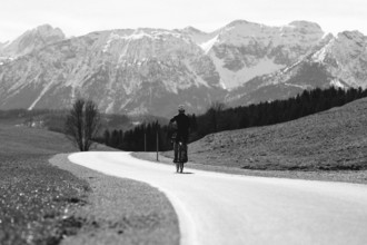 Road bike rider in spring in the Allgäu against the picturesque backdrop of the Alps, Bavaria,