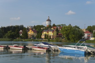 Houses on the lakeshore with boats in the foreground and a water tower surrounded by trees, Elk,