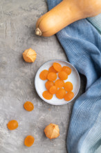 Jelly pumpkin candies on gray concrete background and blue linen textile. close up, top view, flat