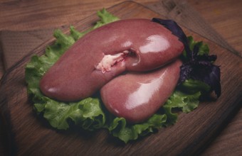 Raw pork kidneys, on a chopping board, close-up, top view, no people