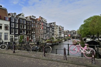 Pink bicycle decorated with flowers on a bridge by a canal, Amsterdam, Province of North Holland,