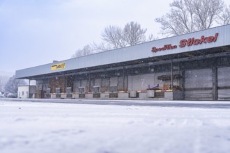 Snow-covered warehouse under cloudy skies with lorry loading, Nagold, Black Forest, Germany, Europe