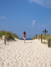 Woman in colourful dress on empty beach, Slovincian National Park, Slowinski Park Narodowy, Poland,