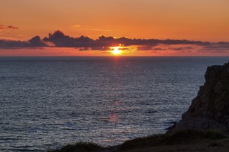 Sunset behind clouds on the Atlantic Ocean, rocky coast Pointe du Van, backlight, Cap Sizun