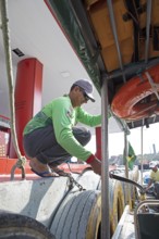 Brazilian man refuelling a boat from a floating petrol station on the Rio Negro, Manaus, Amazonas