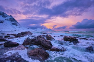 Waves of Norwegian sea on rocky coast in fjord on sunset with sun. Skagsanden beach, Lofoten