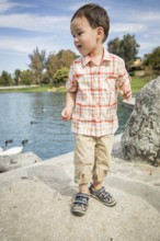 Young chinese and caucasian boy having fun at the park and duck pond