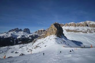 View of a ski resort piste with people skiing in Dolomites in Italy. Ski area Belvedere. Canazei,