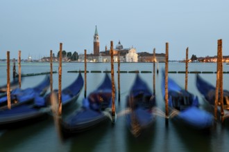 Venetian gondolas near St. Mark's Square in the evening light, blue hour, in the background the