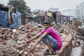 Boy sitting on bricks at a construction site, Tejgaon Slum Area, Dhaka, Bangladesh, Asia