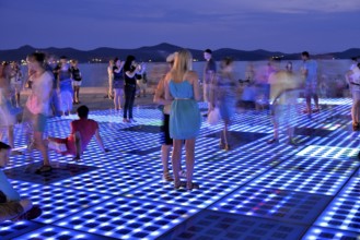 People at the Monument to the Sun, Pozdrav Suncu, by architect Nikole Bašica, at dusk, Zadar,