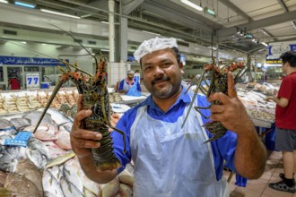 Seller on the fish market with two lobsters, Abu Dhabi City, Emirate of Abu Dhabi, United Arab