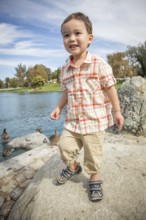 Young chinese and caucasian boy having fun at the park and duck pond