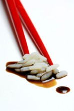 Rice grains on chopsticks, with soy sauce, chopsticks, rice