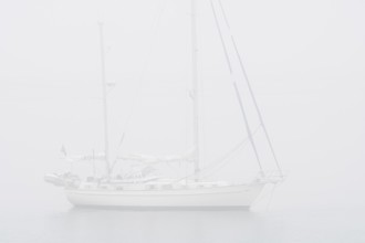 Sailboat, sailing boat, yacht with lowered sails anchored at sea during bad visibility due to thick