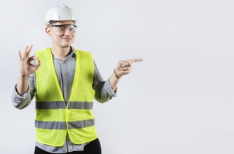 Portrait of male engineer recommending and pointing aside. Smiling engineer pointing and approving