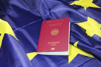 Symbolic image of freedom to travel: German passport on a European flag