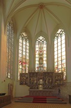 Interior view with high altar and stained glass windows, St Sebastian's Church built in the 14th