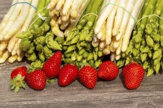 Green asparagus, white asparagus and fresh strawberries decorated on a rustic wooden table