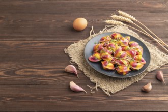 Rainbow colored dumplings with pepper, herbs, microgreen on brown wooden background and linen