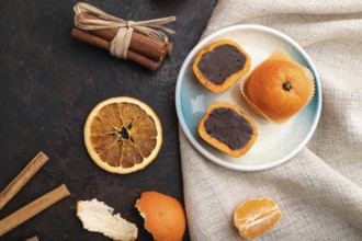 Truffle chocolate tangerine candies on a black concrete background and linen textile. top view,